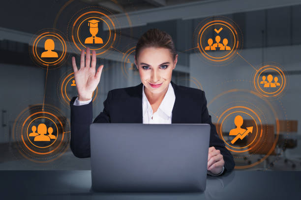 Businesswoman with laptop in office room, waving hand with orange network icons stock photo