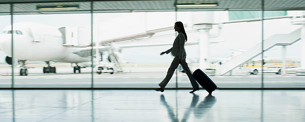businesswoman with suitcase in airport - airport stok fotoğraflar ve resimler