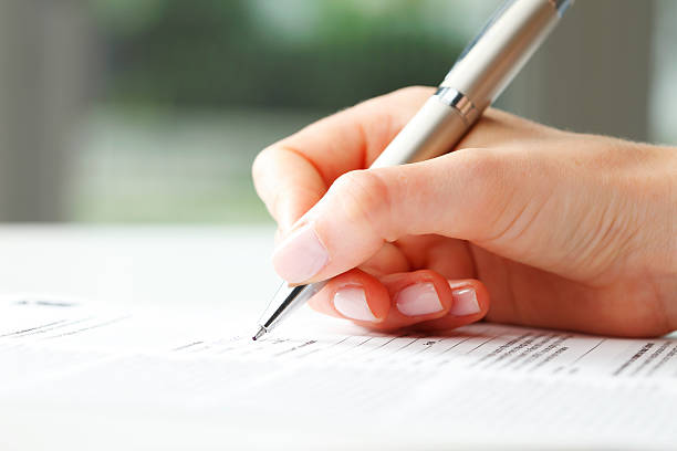 Businesswoman writing on a form Businesswoman's hand with pen completing personal information on a form form document stock pictures, royalty-free photos & images