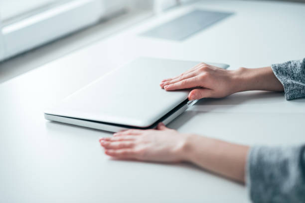 Businesswoman's hands closing or opening laptop on white table in bright office. Businesswoman's hands closing or opening laptop on white table in bright office. closing stock pictures, royalty-free photos & images
