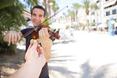 Happy man playing music on violin for money outside
