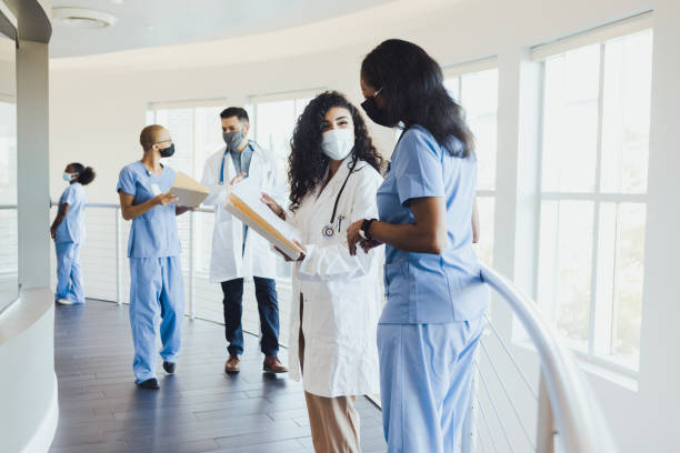 Busy healthcare providers do daily rounds at hospital Wearing protective masks because of COVID-19, busy healthcare professionals do their daily rounds at the hospital. medical student stock pictures, royalty-free photos & images