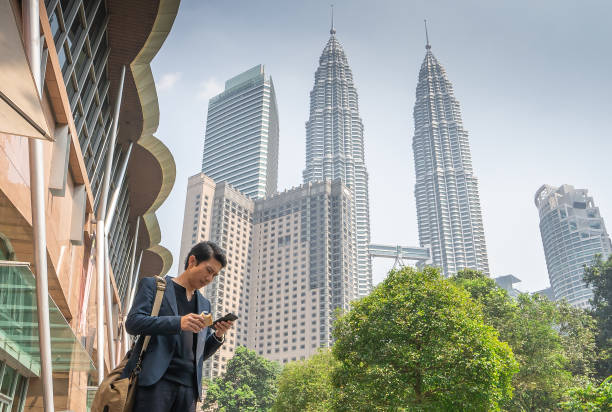Busy Malaysian entrepreneur having lunch break after meeting in KLCC young and busy Malaysia entrepreneur having lunch break after meeting with client in KLCC district, with Petronas twin towers as background bukit bintang stock pictures, royalty-free photos & images