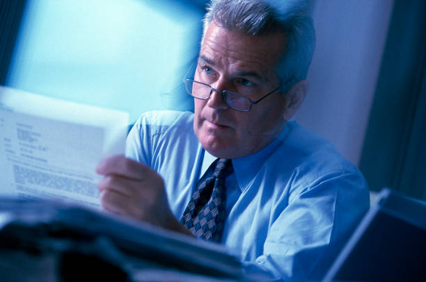 Busy mature (50s) executive in action in office setting. stock photo