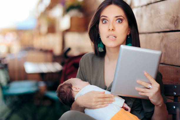 Busy Mom Trying to Work Remotely While Holding Sleeping Baby stock photo