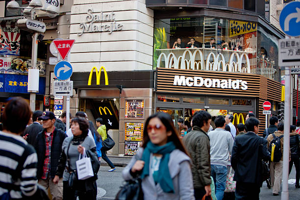 Busy Tokyo Street, crowds and McDonalds Tokyo, Japan - November 6, 2010: Busy Tokyo Street, crowds and McDonalds fast food restaurant, visible people eating inside mcdonalds japan stock pictures, royalty-free photos & images