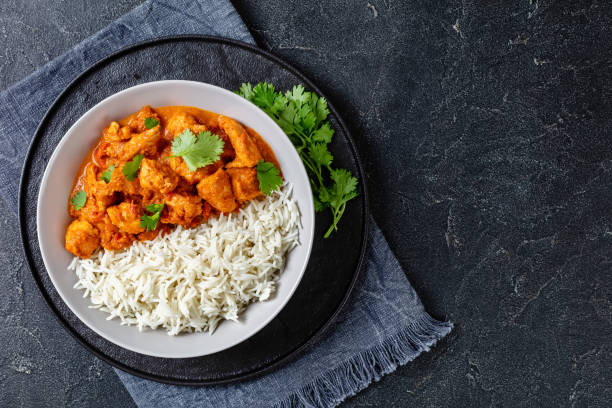 butter chicken with long grain rice and coriander, chicken curry in a bowl on a concrete table, english cuisine, horizontal view from above, flat lay, free space stock photo