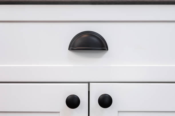 A cabinet cup pull handle on a drawer Photograph of a matte black drawer cup pull handle on a white cabinet. knob stock pictures, royalty-free photos & images