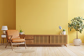 istock Cabinet TV in modern living room with leather armchair and plant on yellow wall background. 1342642875