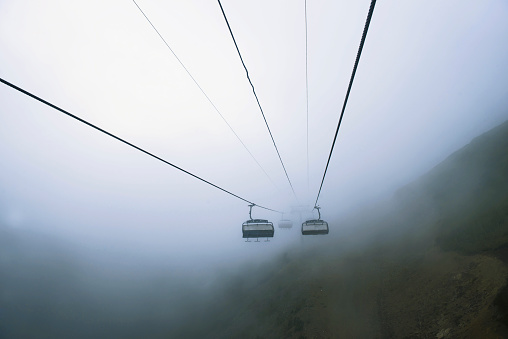 Cable car in the mountains with clouds or fog. View from the cable car to the mountain landscape. without people, suitable for advertising travel agencies and outdoor activities. copy space