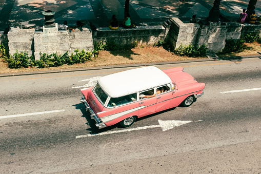 Classic, hot pink Cadillac Bel Air driving down the road in Havana, Cuba.