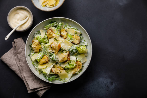 Caesar salad with croutons and parmesan cheese on dark background copy space stock photo