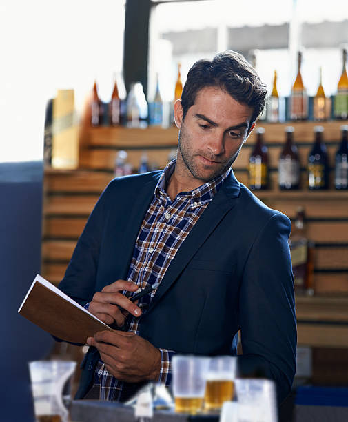 Calculating the consumption Shot of a handsome young man doing stock take at a bar bar drink establishment photos stock pictures, royalty-free photos & images