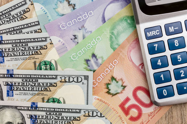 calculator with dollar usd and cad on desk stock photo