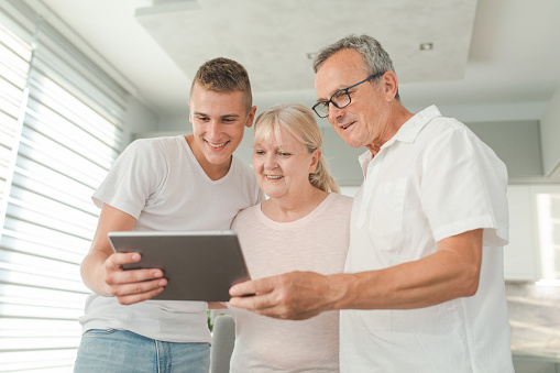 Senior couple and their teenager grandson using digital tablet to make a video call