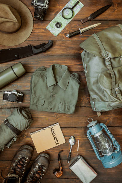Camping gear on wooden floor background Camping gear including knife, clothes, boots, lantern, camera, hat, map, compass. Vertical wanderlust, safari postcard, poster, banner. bushcraft stock pictures, royalty-free photos & images