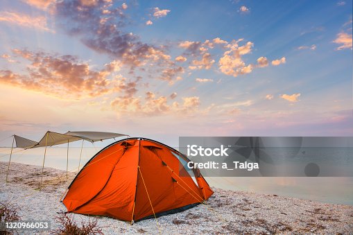 istock Camping tent on a beautiful quiet beach near the water against  the sunset sky background, happy summer time 1320966053