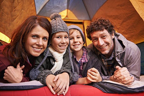 A happy young family lying in a tent while on a camping trip