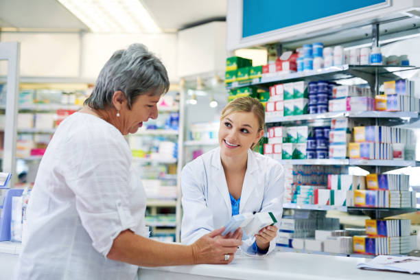Can I recommend this? Shot of a young pharmacist assisting a customer pharmacy stock pictures, royalty-free photos & images