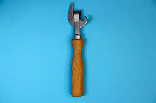 Can opener with wooden handle on blue background, vertical position