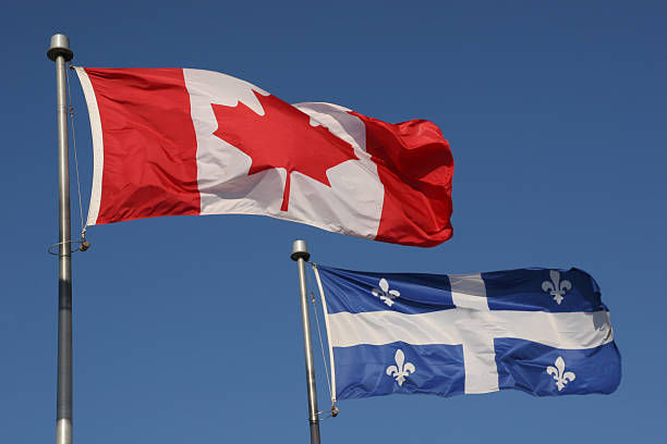 Canadian and Quebec provincial flags flying in a blue sky stock photo