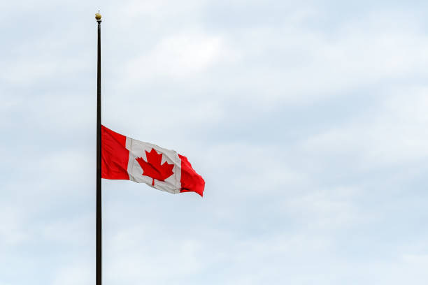 Canadian Flag At Half Mast A Canadian flag at half mast, lowered in remembrance of the indigenous children who were abused and dies in residential schools. Overcast, wide view. flag at half staff stock pictures, royalty-free photos & images