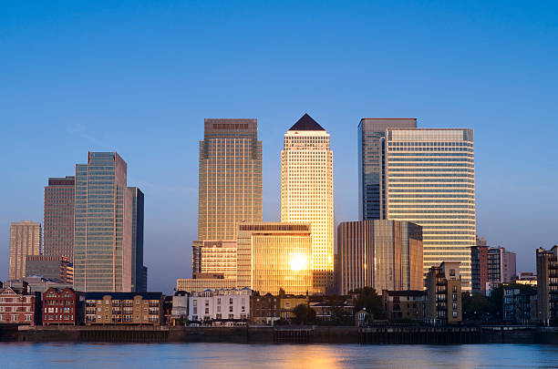 Canary Wharf skyscrapers sunrise, London The rising sun lights up the skyscrapers of Canary Wharf. Canary Wharf is a business and financial district located in London's old docklands it contains the headquarters of several major financial services companies. canary wharf stock pictures, royalty-free photos & images
