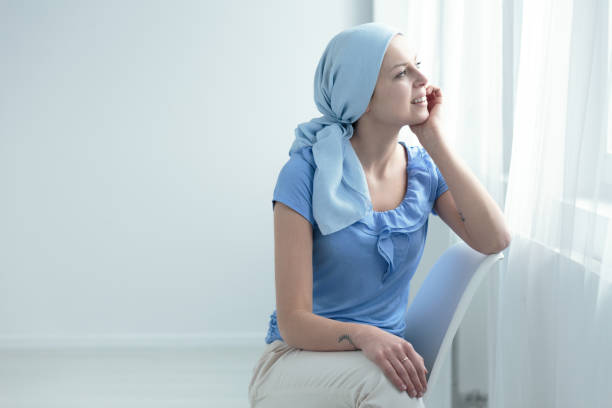 Cancer survivor sitting on chair Breast cancer survivor sitting on a white chair, happily looking out the window cue ball stock pictures, royalty-free photos & images