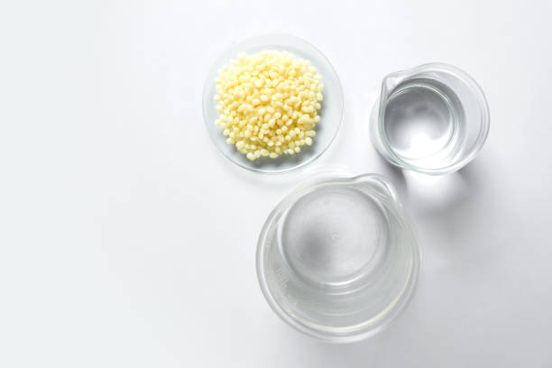 Candelilla Wax in Chemical Watch Glass and alcohol in beaker place on white laboratory table. Top view stock photo