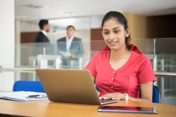 Candid portrait of young woman using laptop Sri Lankan businesswoman in modern office with computer, concentrating sri lanka women stock pictures, royalty-free photos & images