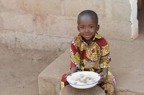 Candid Shot of Little Black African Boy Eating Rice Outdoors stock photo