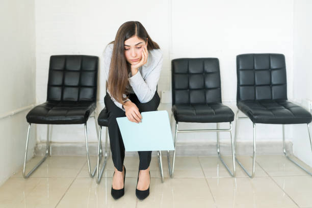 Candidate Waiting For Her Turn In Job Interview At Office Bored Hispanic female applicant sitting with resume in waiting room during recruitment at office unemployment stock pictures, royalty-free photos & images