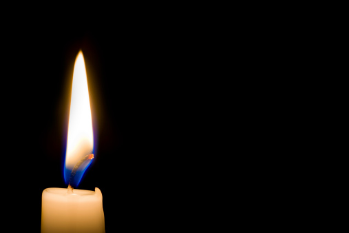Close up of candle flame isolated on black background, horizontal with copy space on right.