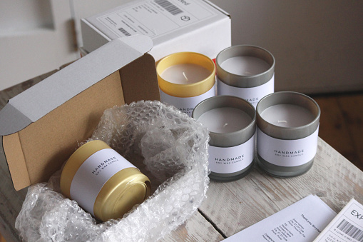 A small home candle making/crafting business set up with customer orders and parcels in shot. Fictional labels, invoices and product labels used.