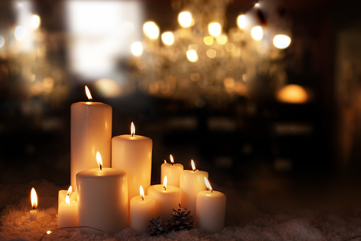 Burning candles in snow festively decorated. Christmas and advent background with golden bokeh lights and short depth of field. space for text.