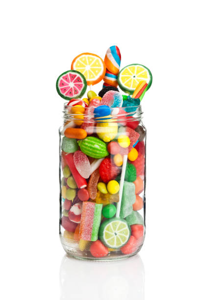 Candy jar on white background Front view of an open candy jar filled with multi colored candies and jelly beans standing on white background. Some candies are spilled out of the jar directly on the background. DSRL studio photo taken with Canon EOS 5D Mk II and Canon EF 100mm f/2.8L Macro IS USM candy jar stock pictures, royalty-free photos & images