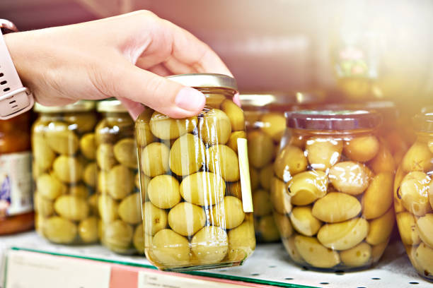Canned olives in hands buyer in shop Canned olives in the hands of a buyer in a store green olives jar stock pictures, royalty-free photos & images