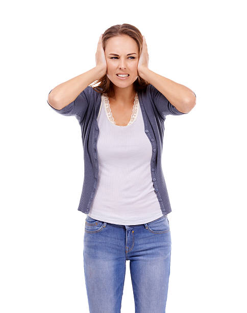 I can't take this noise! Casually dressed woman blocking her ears with a frown - isolated on white Fingers in Ears stock pictures, royalty-free photos & images