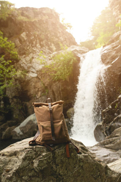canvas backpack in the forest by the waterfall stock photo