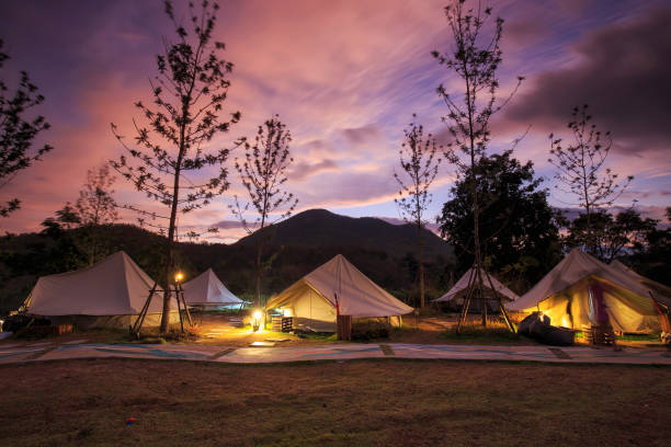 Canvas glamping bell tents in a green field with walkway at mountain view in beautiful sky with cloud before sunrise. stock photo