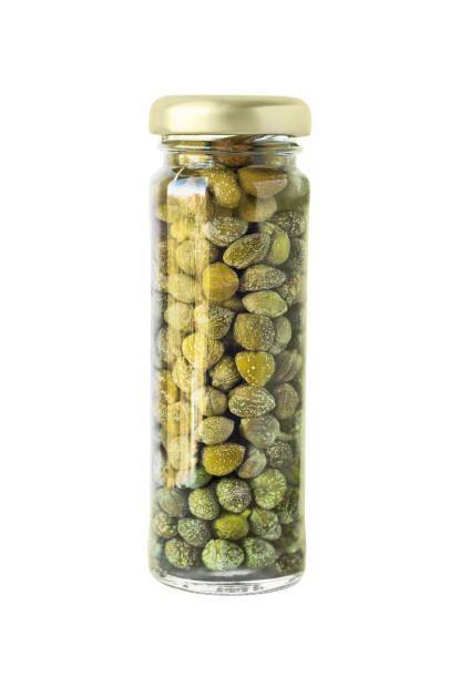 Capers Salted or pickled canned capers in glass jar. Food ingredient isolated on white background caper stock pictures, royalty-free photos & images