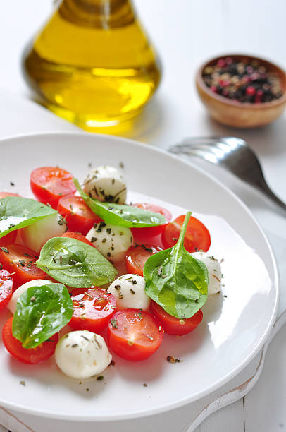 Caprese Salad on white plate with olive oil on wooden background