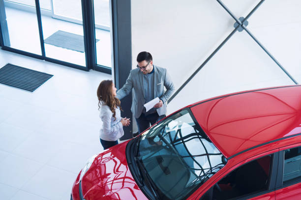 Car dealership. Car dealer presenting perfect city car for an attractive businesswoman. happy people buying new vehicle automobile. car salesperson stock pictures, royalty-free photos & images