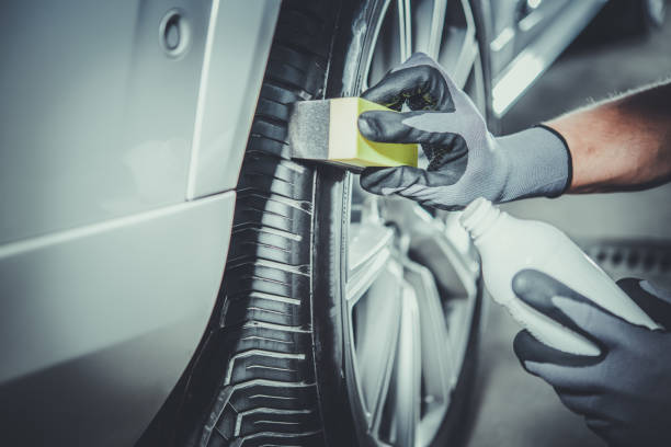 Car Detailing Worker Taking Care of Vehicle Tires and Alloy Wheels stock photo