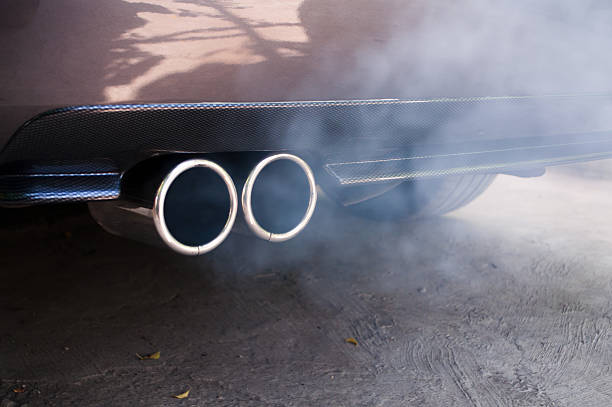 Car exhaust pipe expelling smoke stock photo