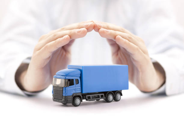 Car insurance. Blue truck miniature covered by hands. stock photo