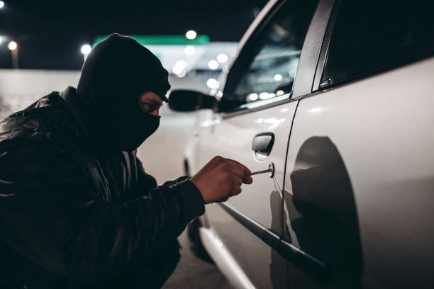 Car jacking Caucasian man with ski mask stealing a car at night. steal stock pictures, royalty-free photos & images