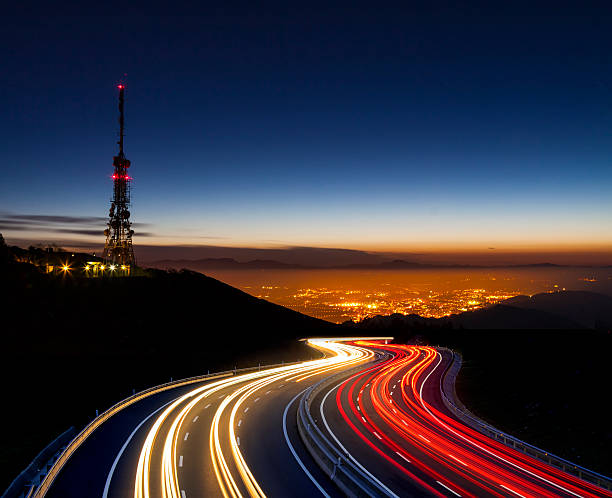 car lights at night towards the city and communications antenna car lights at night towards the city and communications antenna communications tower photos stock pictures, royalty-free photos & images