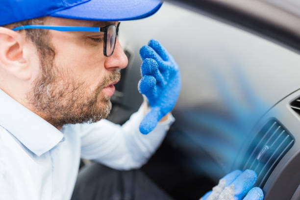 Car maintenance worker feeling bad smell from air conditioning system. Car reparation concept. stock photo