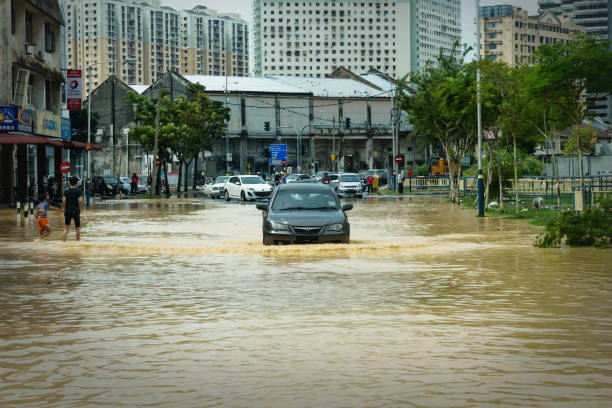 auto fährt nach heftigen regenfällen in georgetown, penang, malaysia auf überfluteter straße ins hochwasser - motorrad fluss stock-fotos und bilder
